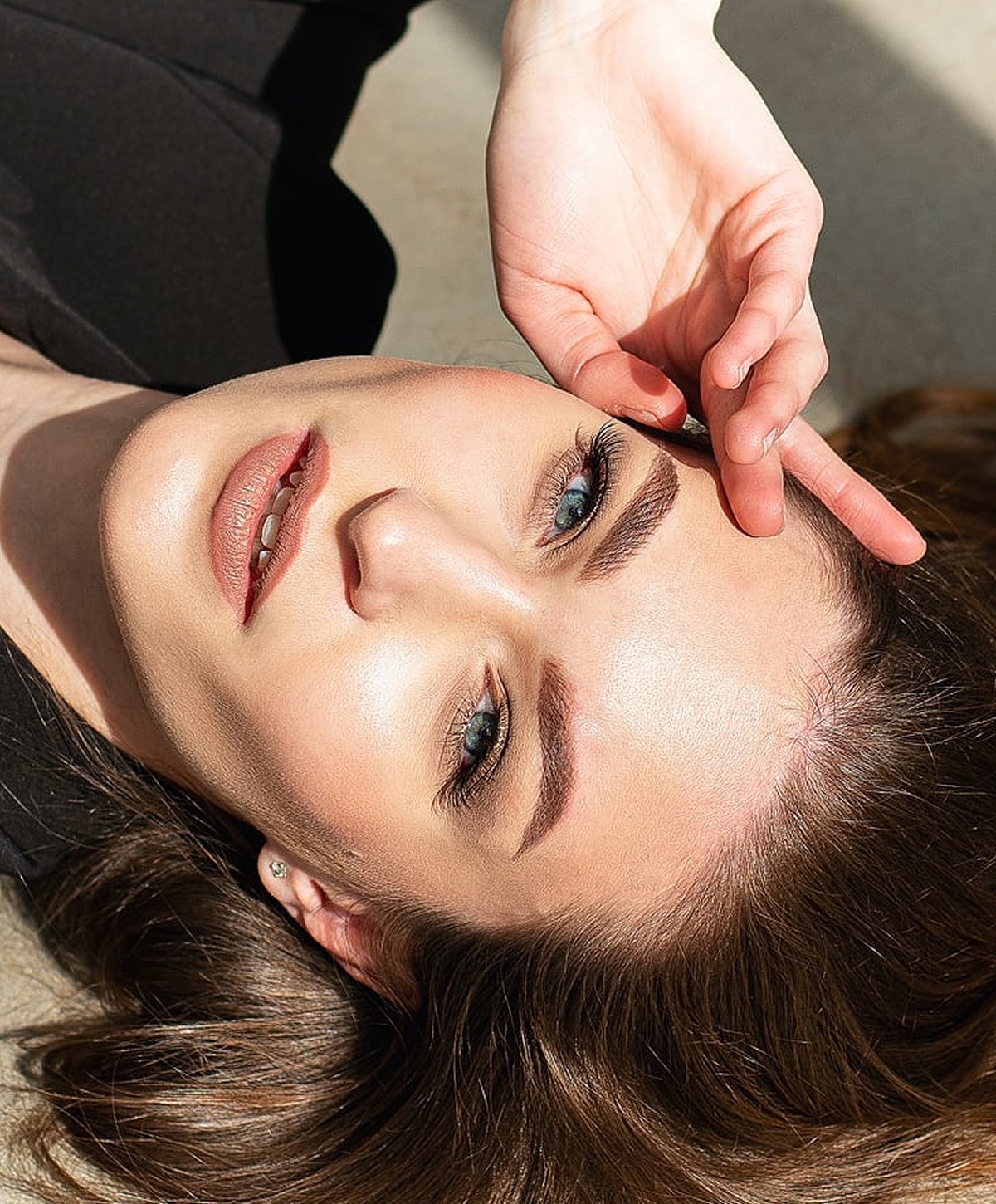Woman with stylish makeup lying on ground.