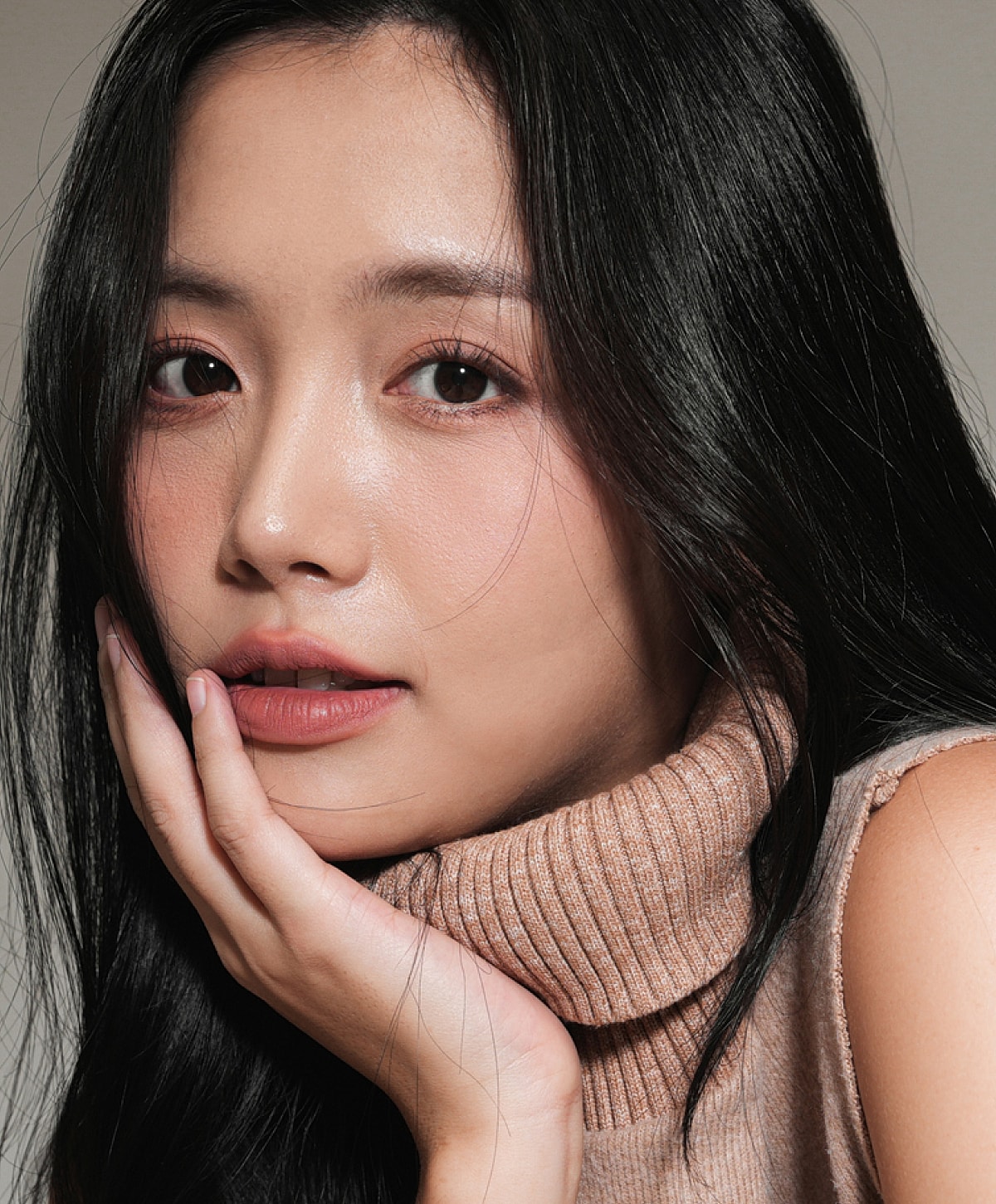 Woman with long hair resting her chin on hand.