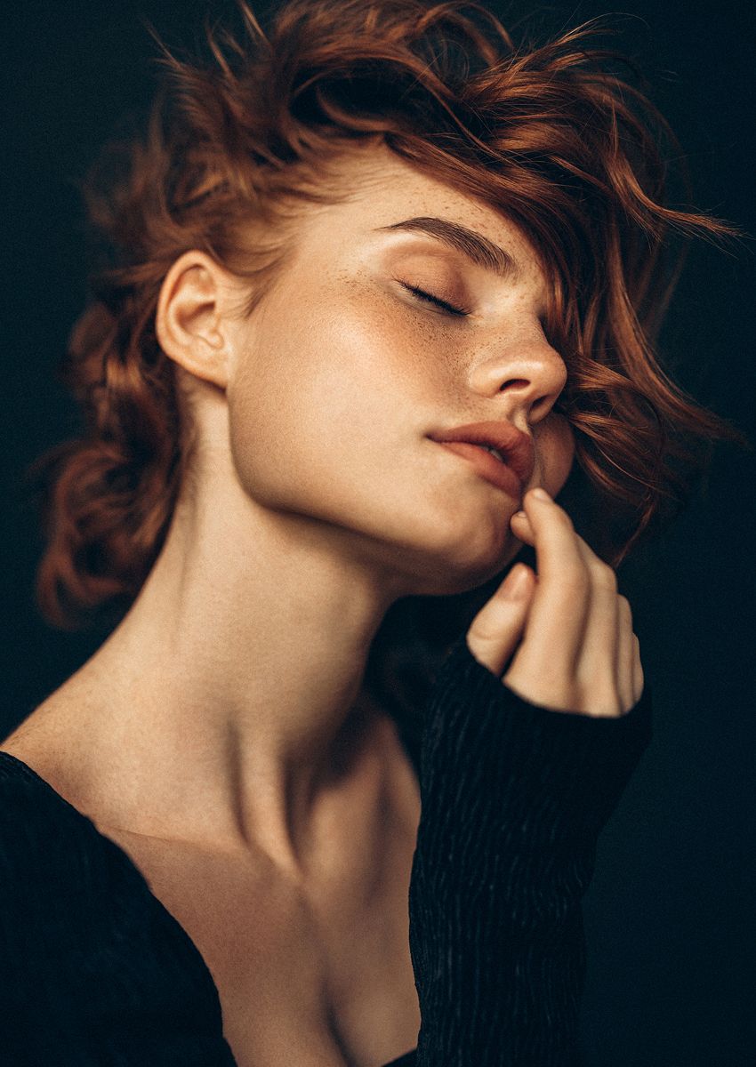 Woman with tousled hair and serene expression.