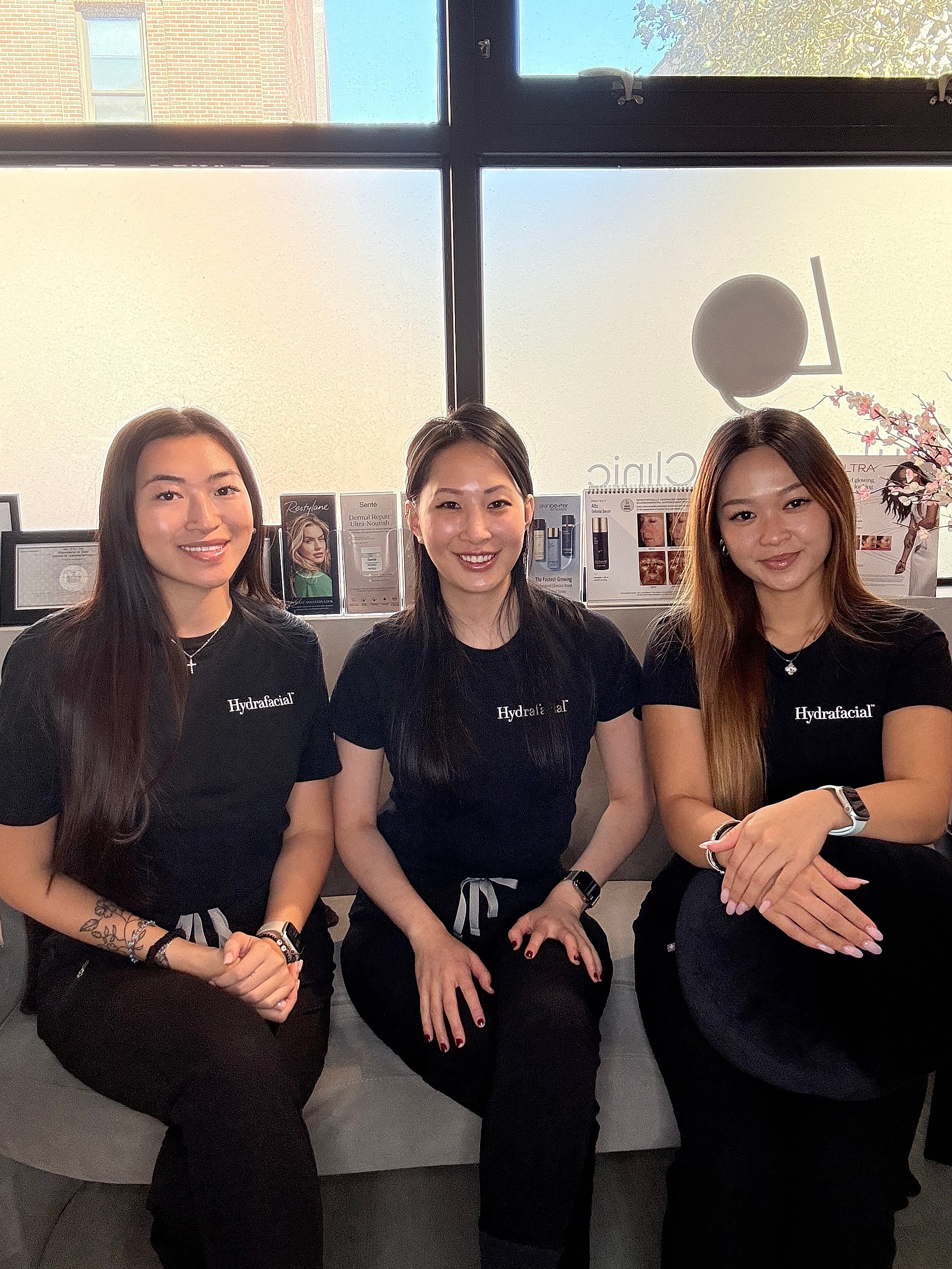 Three women at a skincare clinic, smiling together.
