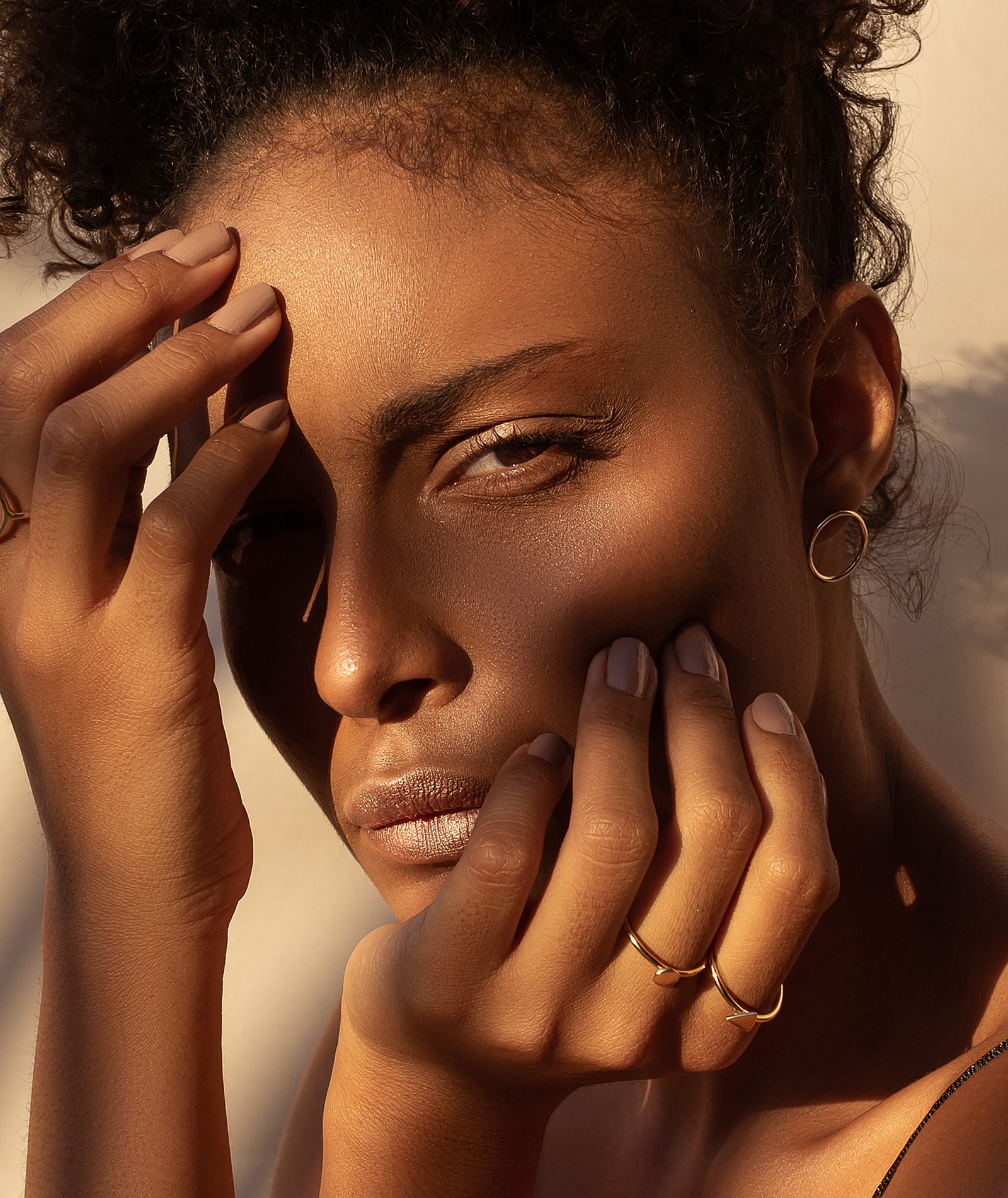 Woman with hands on face, natural light portrait.